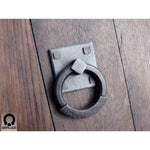 wrought iron ring pull with square backplate attached to a wooden door